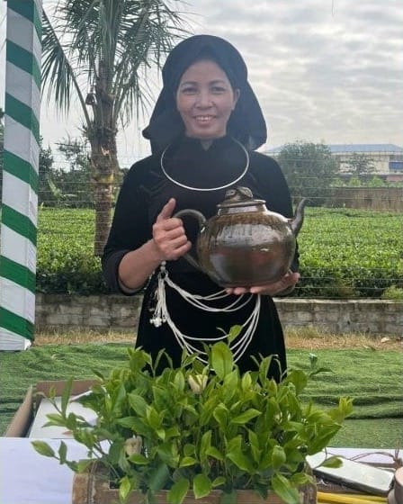 Ma Thi Tuyen, artisane du thé chez TRAVINA, plus de 35 ans de chauffe à la poêle, une théière à la main près des jardins de thé de la coopérative