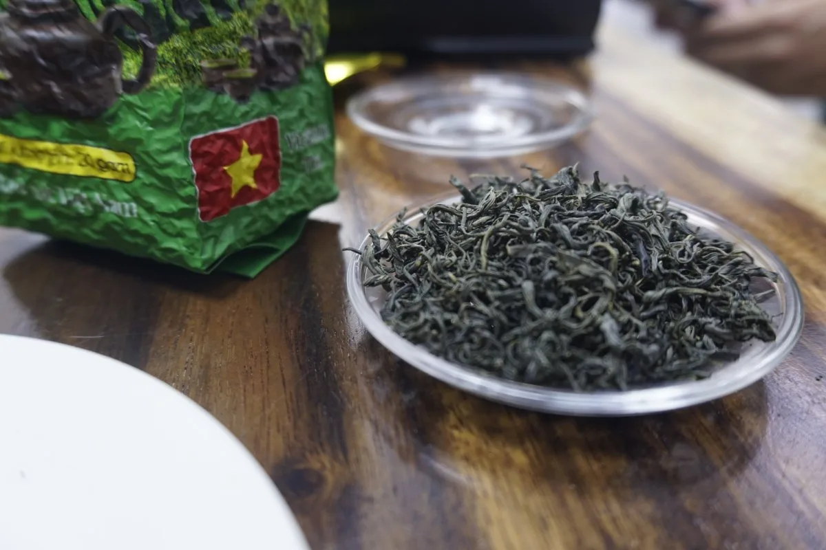Dry moc cau tea leaves beside a TRAVINA pack, photographed at the cooperative