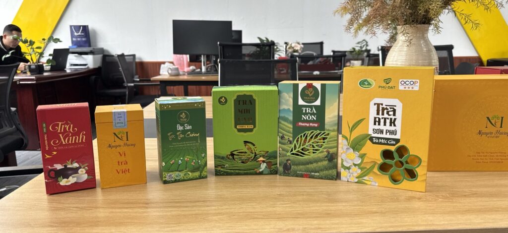 Drei TRAVINA-Teeboxen auf einem Tisch neben Boxen von Nguyen Huong und Phu Dat, Genossenschaften, mit denen TRAVINA zusammenarbeitet