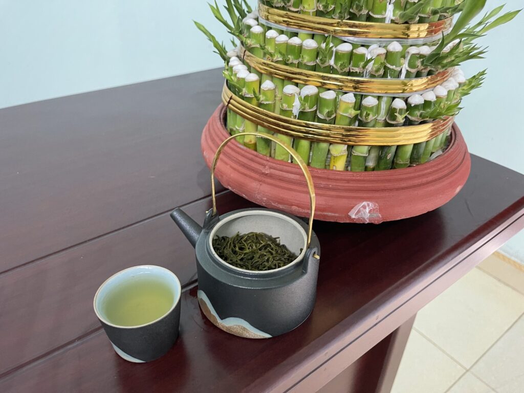Eine Tonkanne mit grünem TRAVINA-Tee und eine eingeschenkte Tasse auf dem Tisch im Büro der Genossenschaft