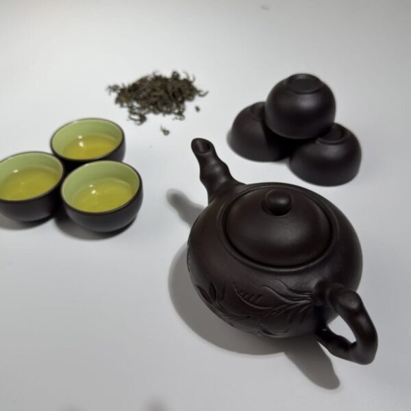 Théière et tasses en argile zisha à côté de thé vert de Thai Nguyen en vrac